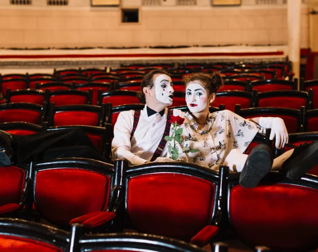 female-male-mime-artist-sitting-together-arm-chair-with-rose